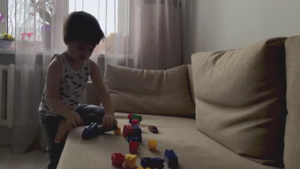 Un niño juega en el diseñador en la habitación — Vídeo de stock
