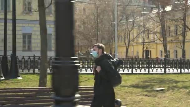 Москва, Россия-март 2020 года. мужчина в защитной маске от ковид-19, идущий один по центру города, никого вокруг . — стоковое видео