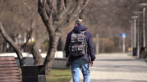 Moskou, Rusland-maart 2020.man met beschermmasker van covid-19, wandelingen in het park helemaal alleen. — Stockvideo