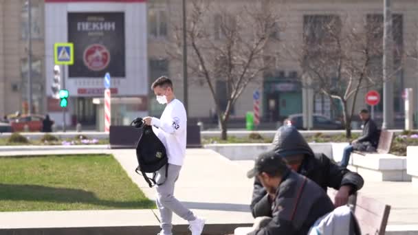 Moscovo, Rússia-Março 2020.jovem em máscara protetora de covid-19, coloca fones de ouvido e desce a rua — Vídeo de Stock