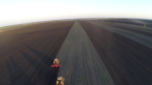 Некоторые тракторы могут вспахать поле на рассвете — стоковое видео