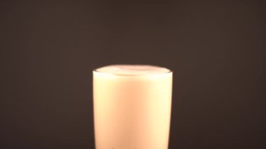 Çikolata parçaları bir bardak kapuçinonun içine düşüyor, ağır çekimde. Özel odak