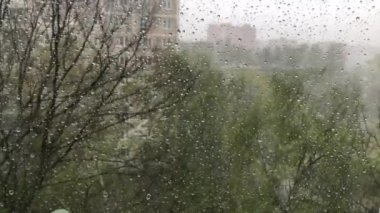 Pencerenin dışında şiddetli yağmur ve güçlü rüzgar damlaları pencereden aşağı akıyor.
