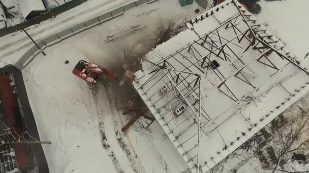 Excavatrice démolir vieille maison délabrée en hiver. Vue aérienne — Video