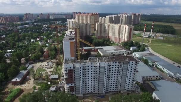 Robotnicy budowlani budujący budynek mieszkalny na polu, widok z powietrza — Wideo stockowe