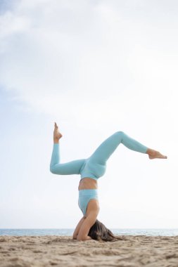 Güneşli bir günde Barselona İspanya 'da deniz kenarındaki kumsalda yoga yapan formda bir kız.