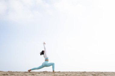 Güneşli bir günde Barselona İspanya 'da deniz kenarındaki kumsalda yoga yapan formda bir kız.
