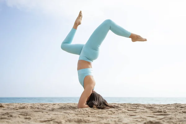 Güneşli bir günde Barselona İspanya 'da deniz kenarındaki kumsalda yoga yapan formda bir kız.