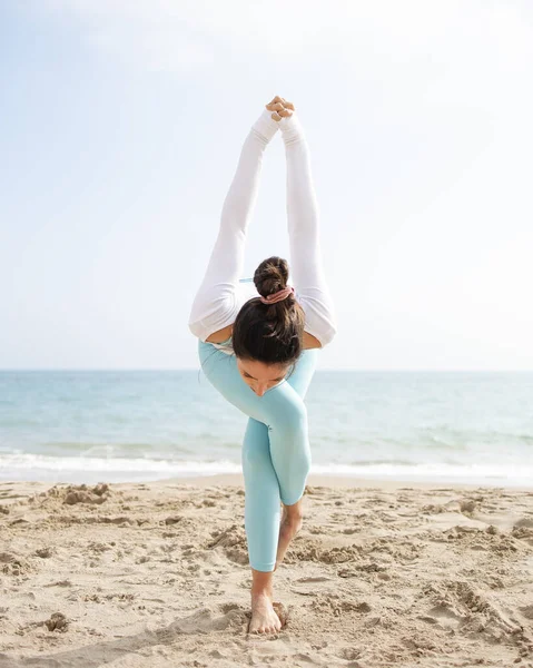 Güneşli bir günde Barselona İspanya 'da deniz kenarındaki kumsalda yoga yapan formda bir kız.