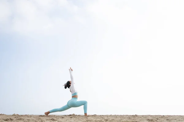 Güneşli bir günde Barselona İspanya 'da deniz kenarındaki kumsalda yoga yapan formda bir kız.