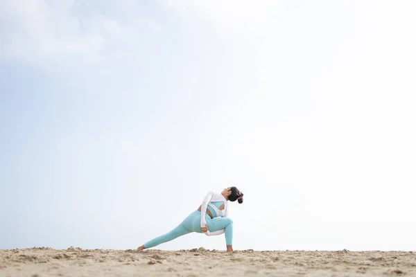 Güneşli bir günde Barselona İspanya 'da deniz kenarındaki kumsalda yoga yapan formda bir kız.