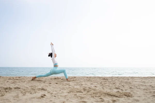 Güneşli bir günde Barselona İspanya 'da deniz kenarındaki kumsalda yoga yapan formda bir kız.