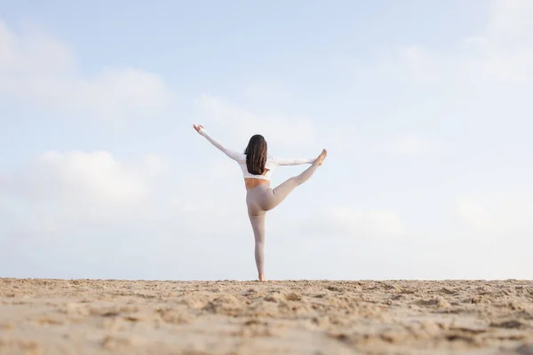 Güneşli bir günde Barselona İspanya 'da deniz kenarındaki kumsalda yoga yapan formda bir kız.