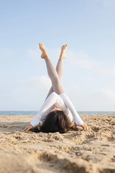 Güneşli bir günde Barselona İspanya 'da deniz kenarındaki kumsalda yoga yapan formda bir kız.