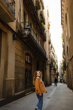 Barselona 'da sokaklarda yürüyen bir kız. Sarışın, kıvırcık saçlı, Barselona sokaklarında yürüyen binalara bakan ve turizm yapan tatlı bir kız..