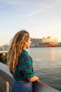 Rambla de Mar 'daki Ramblas' ın sonundaki Barcelona 'da denize bakan kıvırcık saçlı şık sarışın kız..
