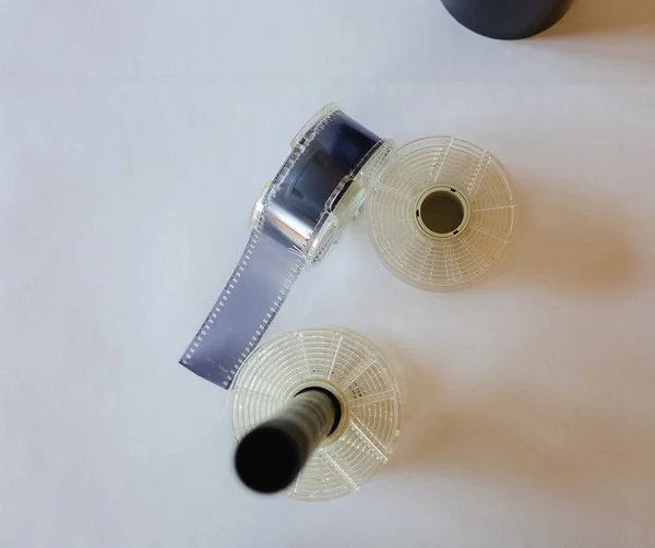 Karanlık odada 35 mm 'lik film geliştirmek için alet çantası. Film makaraları ve film tankı beyaz bir arkaplanda masanın üstünde..