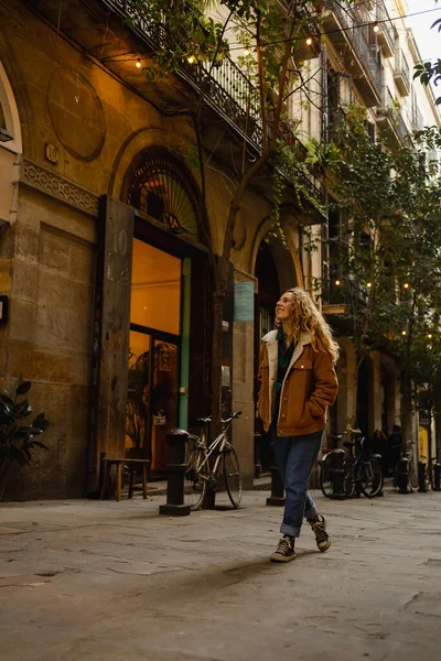 Barselona 'da sokaklarda yürüyen bir kız. Sarışın, kıvırcık saçlı, Barselona sokaklarında yürüyen binalara bakan ve turizm yapan tatlı bir kız..