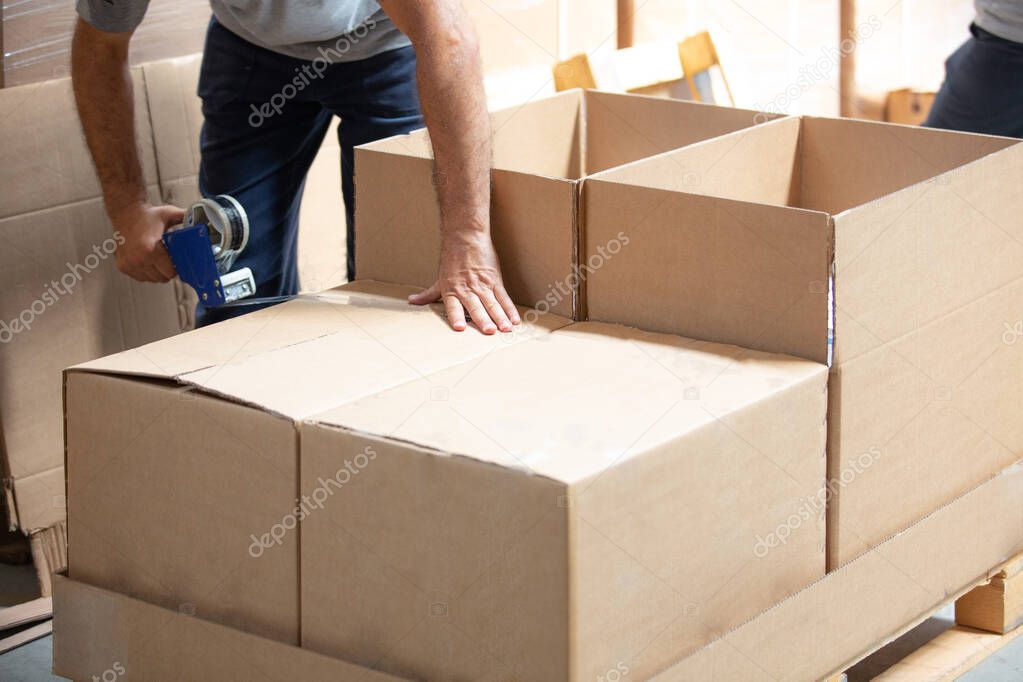 Man packing with adhesive tape in warehouse
