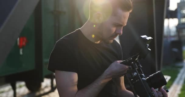 Homme Cinéaste en film noir tenu à la main le coucher du soleil. Images industrielles ensoleillées — Video