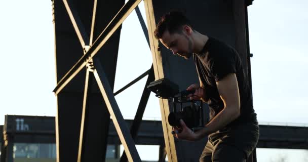 Męski filmowiec w czarnym filmie trzymający za rączkę zachód słońca. Biznes — Wideo stockowe