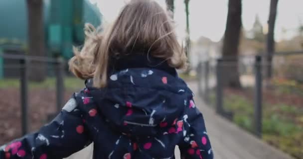 Mała dziewczynka w sukience z róży ucieka przed kamerą. — Wideo stockowe