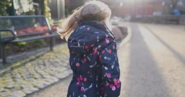 Güllü elbiseli küçük bir kız kameradan kaçıyor.