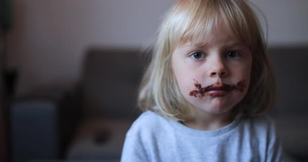 Zbliżenie zabawna mała dziewczynka jedząca czekoladę. Brązowe usta i zęby. — Wideo stockowe