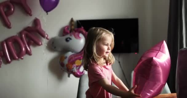 Blond little girl opens the gifts. Child looks in the box, is surprised — Stock Video