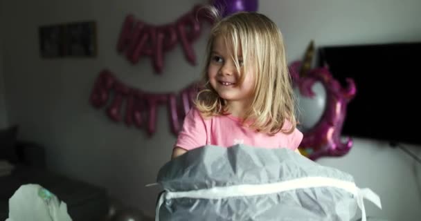 Blond meisje opent de cadeaus. Kind kijkt in de doos, is verrast — Stockvideo