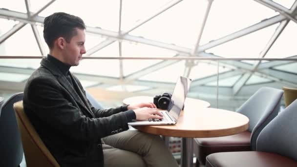 Killen jobbar på ett kafé på en laptop. — Stockvideo