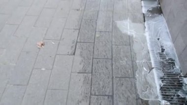 Yakın plan erkek ayakları şehrin duvarının yanında buzun üzerinde süzülüyor.