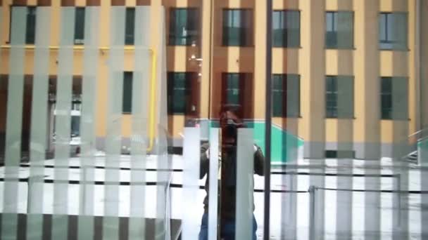 Un hombre con una cámara quita una ventana espejada de las persianas — Vídeo de stock