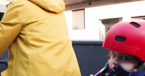 Дитина в шоломі їде з матір'ю на дитячому велосипедному сидінні — стокове відео