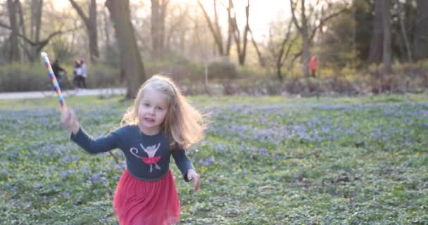 Ragazza bionda volteggia felicemente in un bel vestito nel parco primaverile — Video Stock