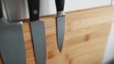 Ahşap bir manyetik levhanın üzerinde mutfak bıçaklarının olduğu duvara yakın plan.