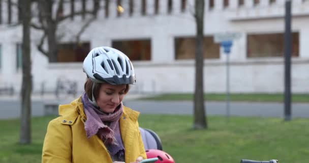 戴着头盔的金发姑娘在自行车前停下，看了一个智能手机短信，笑了 — 图库视频影像