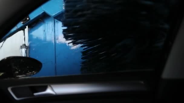 Samochód w myjni myje szczotki na tle niebieskiego sprzętu — Wideo stockowe