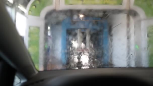 El parabrisas del coche delante del equipo dentro del lavado de coches — Vídeo de stock