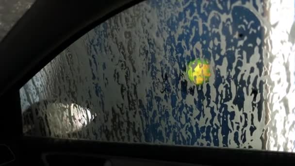 Strumienie piany spływają z boku samochodu w myjni samochodowej. — Wideo stockowe
