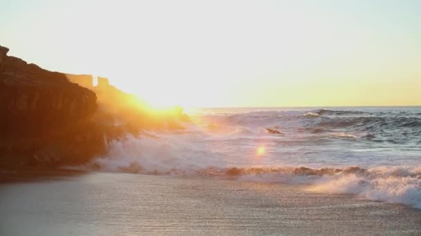 Frothy waves break against a rocky rock on the ocean at sunrise — Stock Video