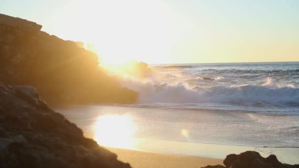 Una ola espumosa golpea las rocas al amanecer — Vídeos de Stock