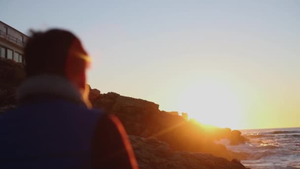 Um homem caminha ao longo do oceano para encontrar o nascer do sol — Vídeo de Stock