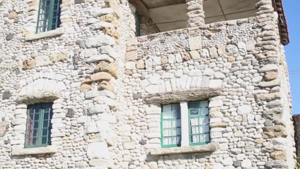 Ancienne maison en pierre avec barreaux dans les fenêtres contre le ciel bleu — Video