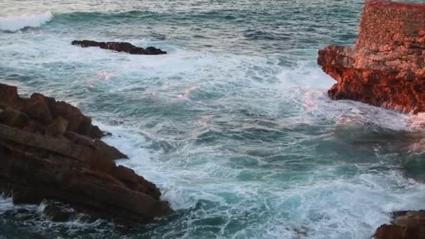 Пенные волны разбиваются о скалы берега океана — стоковое видео