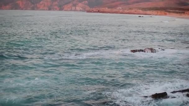 Mar azul calmo em uma lagoa com costas marrons rochosas — Vídeo de Stock