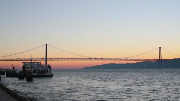 El sol sale por encima del puente del río con el barco en el muelle — Vídeos de Stock