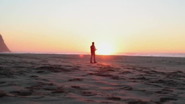 Ein Mann steht vor dem Hintergrund der Sonne am wolkenlosen Himmel — Stockvideo