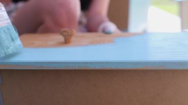 Güzel sarışın caddede ahşap bir kapı boyuyor mavi boya