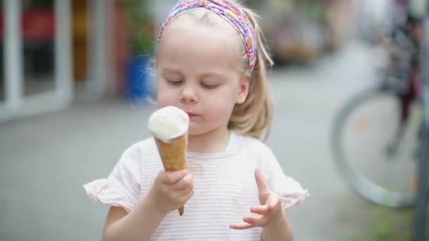 Little blonde eats on the street in summer ice cream with waffle horn — Stock Video